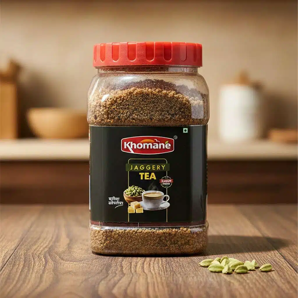 Khomané Elaichi Jaggery Tea jar with cardamom pods and a cup of tea.